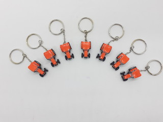 Unique Special Designed Key Chain with Orange Black Wheels Tractor Toys for Souvenir Gift Farming Exhibition in White Isolated Design