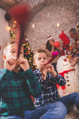 Boys celebrating Christmas with family, blowing party whistles