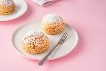 Craquelin Choux biscuits with cream filling on a pink background.