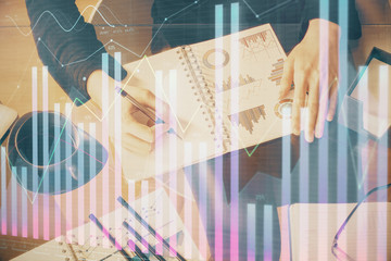 Double exposure of hands making notes with forex chart huds. Stock market concept.