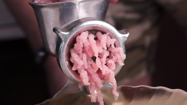 Cooking minced meat with a manual meat grinder. Close-up of front part of mincing-machine with mincemeat in. Showing the forcemeat process.