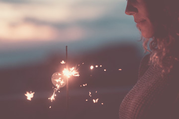 Close up of sparler light fireworks and beautiful caucasian woman face -c oncept of people...