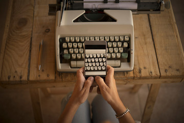 Concept of write and work  with old and modern new technlology - typwriter and modern cellular mobile phone taking picture at the keyboard with letters - woman hands worker people