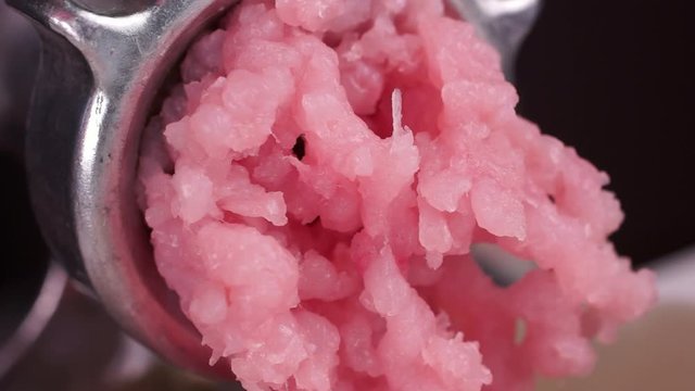 Cooking minced meat with a manual meat grinder. Close-up of front part of mincing-machine with mincemeat in. Showing the forcemeat process.