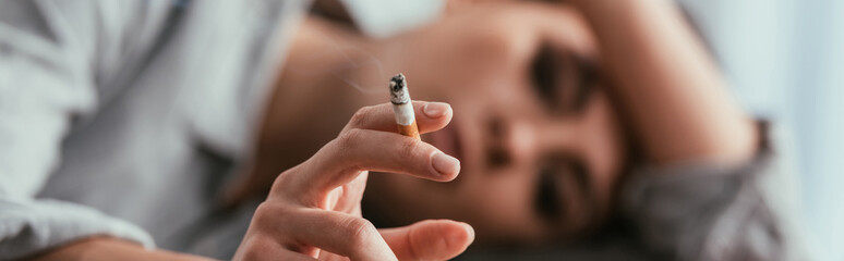 Selective focus of woman holding cigarette, panoramic shot