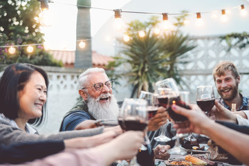 Happy family dining and toasting red wine glasses outdoor - People with different ages and...