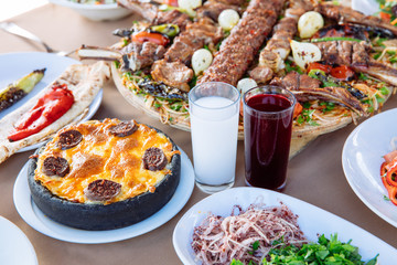 Traditional Turkish Adana kebab or kebap meat food, appetizers, raki and salgam on table from top view in turkish restaurant.	