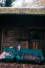 Wooden hut in the woods with coach and armchair in front