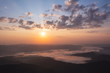 Colorful sunrise in the mountains. Beautiful sunrays and clouds over the lake