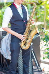 Obraz premium Gorgeous saxophonist lady is playing saxophone in wedding ceremony. musician woman. attractive woman and music instrument . classical and romantic happiness events. image for objects and copy space.