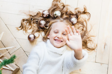 Girl lying on the floor in her hair balls for Christmas tree