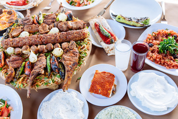 Traditional Turkish Adana kebab or kebap meat food, appetizers, raki and salgam on table from top view in turkish restaurant.	