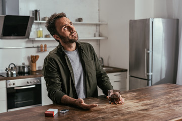 Man holding whiskey glass and looking up at kitchen table