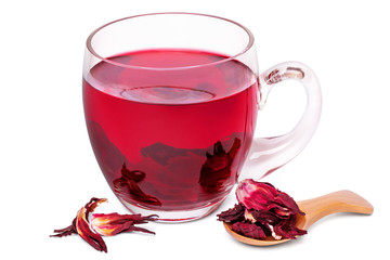 Hibiscus tea in a glass mug and dried calyces in a wooden spoon