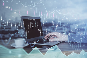Double exposure of businessman's hands with laptop and stock market graph background. Concept of...