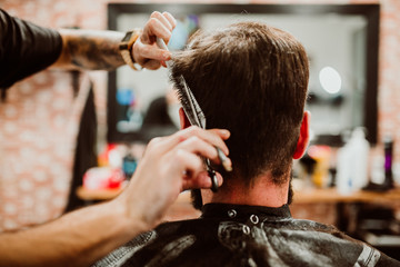 .Young hipster man with hearty beard cutting his hair in a barbershop. Professional hairdressing work. Lifestyle..