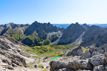 Wild alpine landscape with rocky mountains, green grass and blue sky in the Lechtal Alps, Tirol, Austria