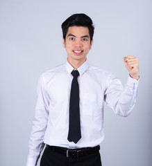 Portrait handsome young asian .businessman wearing a white shirt excitement or celebrating his victory sign isolated on grey background in studio. Asian man people. business success concept.