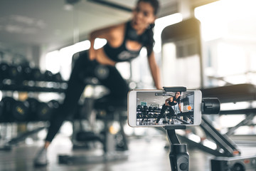 Woman using a phone for vlogging or selfie photo. Asian woman doing workout with dumbbell