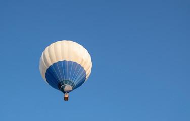 Blue and white hot air balloon flying in blue sky