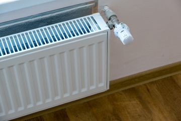 Closeup of heating radiator valve for comfortable temperature regulation on metal radiator on inrerior wall.