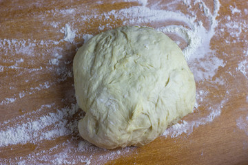 Dough ball on the table sprinkled with flour. Dough for baking dessert or pizza.
