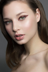 Beautiful woman with bright make up eye with sexy red liner makeup. Fashion big arrow shape on woman's eyelid. Natural lips. Chic evening make-up. Luxurious long wave hair. Shining face skin