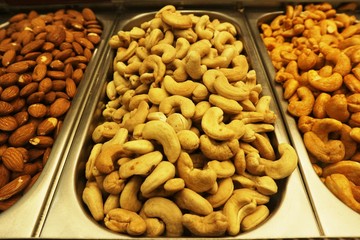 Selection of nuts on display in shop in stainless steel containers