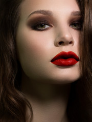 Beautiful brunet model woman face with green eyes and perfect make-up. Portrait of beauty young brunet girl with red lips and smoky eyes, thick eyesbrow . Female face with clear skin close-up.