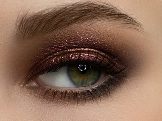 Elegance close-up female eye with dark brown eyeshadow. Macro shot of part of the face of a...