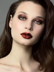 Close up a beauty portrait with beautiful fashionable evening make-up, black smoky eyes and extremely long eyelashes. Brown lipstick on the lips. Cosmetology and spa facial skin care