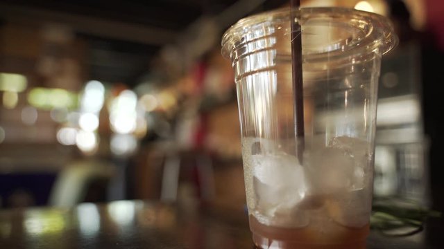 Cup of empty iced coffee with plastic straw in Asian style cafe