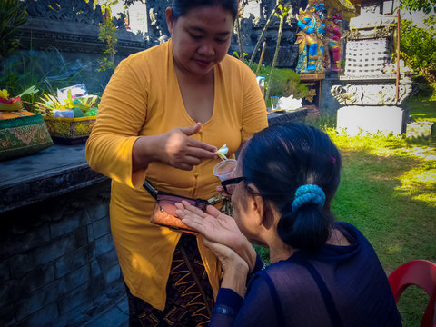 Balinese Family Ceremony Grandmother Is Sprinkled With Holy Water By Her Daughter In Law At Dalem Temple, Bali, Indonesia