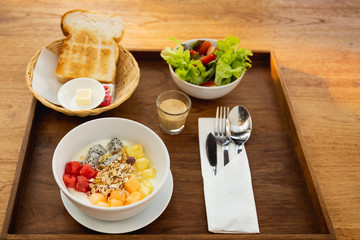 Bowl of muesli with yoghurt and fruit with toast and vegetable salad.