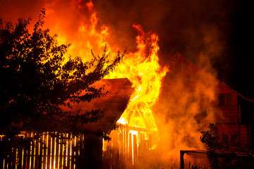 Wooden house or barn burning on fire at night.