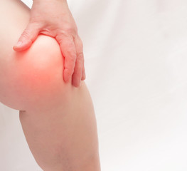 An elderly woman holds on to the knee joint on her leg. Pain and inflammation in the knee, diseases...
