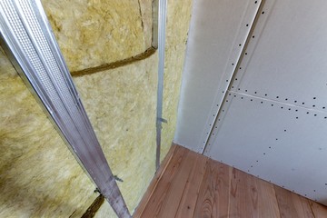 Wall of a room under renovation with mineral rock wool insulation and metal frame prepared for drywall plates. - obrazy, fototapety, plakaty