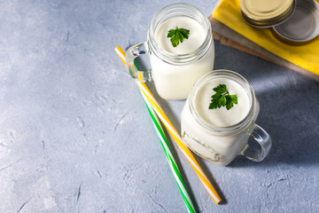 simple homemade kefir in a glass with spices and herbs on a gray background, copy space. Probiotic...
