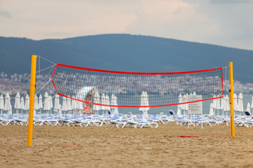 Empty volleyball net on a sandy beach on the sea shore in summer.