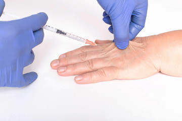 A plastic surgeon doctor does an injection of a beauty injection into the hands of an elderly...