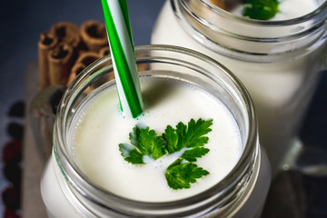 simple homemade kefir in a glass with spices and herbs on a gray background, copy space. Probiotic...