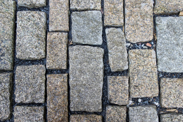 An old stoneblock pavement cobbled with rectangular granite blocks with crushed rock fines between blocks