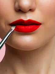 Woman painted red lips. Beauty lips make-up. Perfect skin, full lips. Retro make up. Professional make-up artist applying sexy lips makeup. Fashion makeup