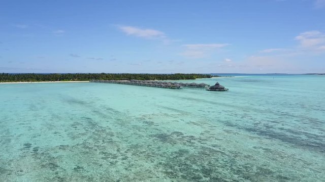 Wide angle shot from drone to Maldives island with blue lagoon abd bungalow 4K