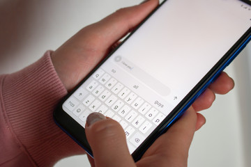 holding a smartphone close-up, writes an SMS message selective focus