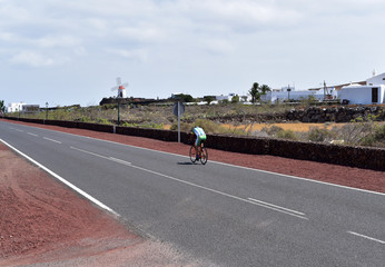 Lone cyclist riding on asphalt road, Lanzarote, Canary Islands, Spain