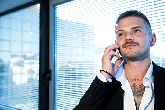 Giovane uomo tatuato parla al telefono