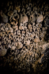 Skulls and bones in Paris catacombs, France. Old broken skull placed on the bones. Underground cemetery.