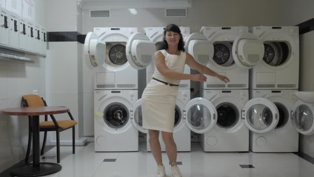 Woman Dancing Viral Dance And Have Fun In The Laundry Room. Happy Business Woman Enjoying Dance, Having Fun Together, Party. Joyful Female In Formal Dress Dancing Cheerful In Laundry Room.