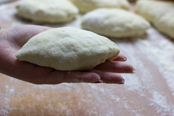 On the palm of a woman cook cooked bun stuffed ready for baking in the oven. Great dessert for tea in the cold season.